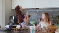 Mom and little daughter cook together in the kitchen, dance and sing to cheerful music. Happy family preparing pie cake Royalty Free Stock Photo