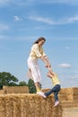 Mom and little daughter have fun on the farm playing on the haystack. Countryside weekends