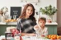 Mom and little daughter in the kitchen decorated for the new year and christmas