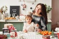 Mom and little daughter in the kitchen decorated for the new year and christmas