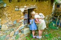 Mom and little daughter look with interest into the window of the old house.Ancient Stone Wall Made of Natural Rough