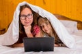 Mom and little daughter lying in bed under a blanket and looking at a laptop Royalty Free Stock Photo