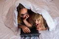 Mom and little daughter lying in bed under a blanket and looking at a laptop Royalty Free Stock Photo