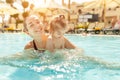 Mom and little daughter are played in the open swimming pool. Family with one child on vacation in warm countries. Positive people Royalty Free Stock Photo