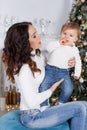 Mom with a little daughter playing on Christmas Eve on the background of a beautiful Christmas tree Royalty Free Stock Photo