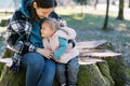 Mom and little girl are hugging on a huge stump covered with moss