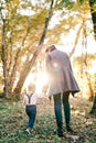 Mom and little girl are walking through the forest in bright sunlight. Back view Royalty Free Stock Photo