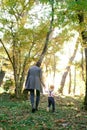 Mom and a little girl are walking up a wooded hill, holding hands. Back view Royalty Free Stock Photo