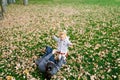 Mom lying on dry foliage stretches out her hands to a little girl standing on a green lawn Royalty Free Stock Photo