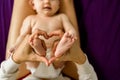 Mom making a heart shape with the feet of her newborn baby