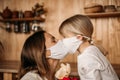 Mom in a mask kisses a little daughter. Blond girl congratulates mom with mother`s day