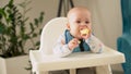 mom Mother feed young baby in white feeding up high chair, first supplement vegetable puree Happy smiling kid eat for Royalty Free Stock Photo