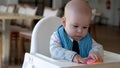 mom Mother feed young baby in white feeding up high chair, first supplement vegetable puree Happy smiling kid eat for Royalty Free Stock Photo