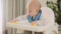 mom Mother feed young baby in white feeding up high chair, first supplement vegetable puree Happy smiling kid eat for Royalty Free Stock Photo