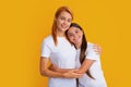 Mom mum and kid daughter in t-shirt embrace cudding isolated on yellow color background studio. Mothers day love family. Royalty Free Stock Photo