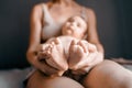 Mom, mummy, young mother with little baby daughter feet, legs in hands. Mum woman hugging child. Newborn cute happy girl Royalty Free Stock Photo