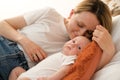 mom with a newborn baby lies on the bed. mother kisses the child. mother's love Royalty Free Stock Photo