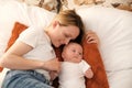 mom with a newborn baby lies on the bed. mother kisses the child. mother's love Royalty Free Stock Photo