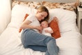 mom with a newborn baby lies on the bed. mother kisses the child. mother's love Royalty Free Stock Photo