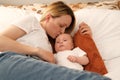 mom with a newborn baby lies on the bed. mother kisses the child. mother's love Royalty Free Stock Photo