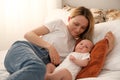 mom with a newborn baby lies on the bed. mother kisses the child. mother's love Royalty Free Stock Photo