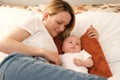 mom with a newborn baby lies on the bed. mother kisses the child. mother's love Royalty Free Stock Photo