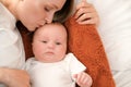 mom with a newborn baby lies on the bed. mother kisses the child. mother's love Royalty Free Stock Photo