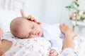 Mom and newborn baby sleep together, mom puts baby to sleep on the bed in the bedroom, the concept of motherhood and healthy sleep