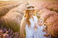 Mom and oddler daughter play with soap bubbles in a field with lavender a