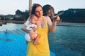 Mom with a one year old baby are standing on the pier. A woman points to the approaching boat and the sea. Tropical island in the Royalty Free Stock Photo