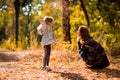 Mom playing with daughter, throw dry yellow fallen leaves. walks in autumn Park Royalty Free Stock Photo