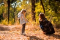 Mom playing with daughter, throw dry yellow fallen leaves. walks in autumn Park Royalty Free Stock Photo