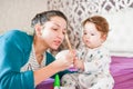 Mom plays with the baby on the bed. Mom plays with baby in the room indoors. Mom plays with the baby in the room indoors