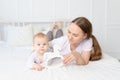 Mom plays with baby wooden toy horse on the bed at home, happy family