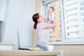 Mom plays with the child at the window in the white kitchen Royalty Free Stock Photo