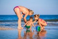 Mom plays with her children: daughter and baby, building beads and castles decorating them with shells Royalty Free Stock Photo