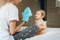 Mom plays with nine-month-old baby girl with soft toy hare. Family leisure. Mom with child play together at home sitting on bed Royalty Free Stock Photo