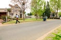 Mom with pram and Mailman delivering mail in a wealthy suburban neighborhood street Royalty Free Stock Photo