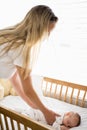 Mom putting baby to sleep in baby bed Royalty Free Stock Photo