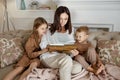 Mom reads a book to the children. A woman tells a story to a boy and a girl before going to bed. Mom daughter and son relax at Royalty Free Stock Photo