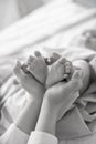 Mom`s hands are holding little cute legs of a newborn baby at home on a white bed Royalty Free Stock Photo