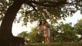 Mom shakes a healthy little daughter on swing under tree in sun. mother plays with child they are swinging on a rope on Royalty Free Stock Photo