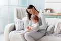 Mom sits on the couch, holding her baby in her lap