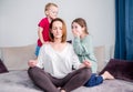 Mom sits on the sofa meditating lotus position, little children scream playing around focused calm mom meditating balancing while