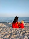 Mom is sitting on the beach, Mother and son in red clothes sit on the beach and hold hands. They are happy. Mother& x27;s Royalty Free Stock Photo