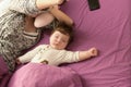 Mom is sleeping with her baby in bed. view from above. purple bed. Young mom and her cute little baby sleeping in bed together,