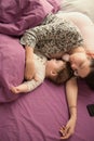 Mom is sleeping with her baby in bed. view from above. purple bed. Young mom and her cute little baby sleeping in bed together,