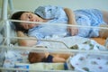 Mom is sleeping in the ward with a newborn baby, a maternity hospital bracelet on her arm. A newly born child in a clinic crib Royalty Free Stock Photo