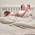 Mom sleeps while father takes care of baby boy, parents and infant child on the home bed. Problems of a man and a woman with a Royalty Free Stock Photo