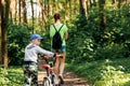 Mom and son with a bicycle stroll through the park, walk in the park opy space for text